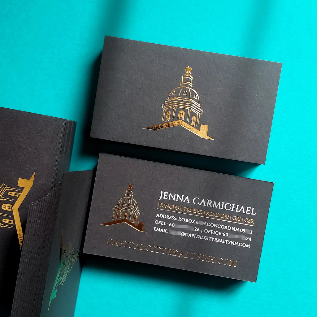 During a client intro the agent slides a weighted 38pt black card across the table, gold stamping visible and white foil contact lines oriented toward the client.