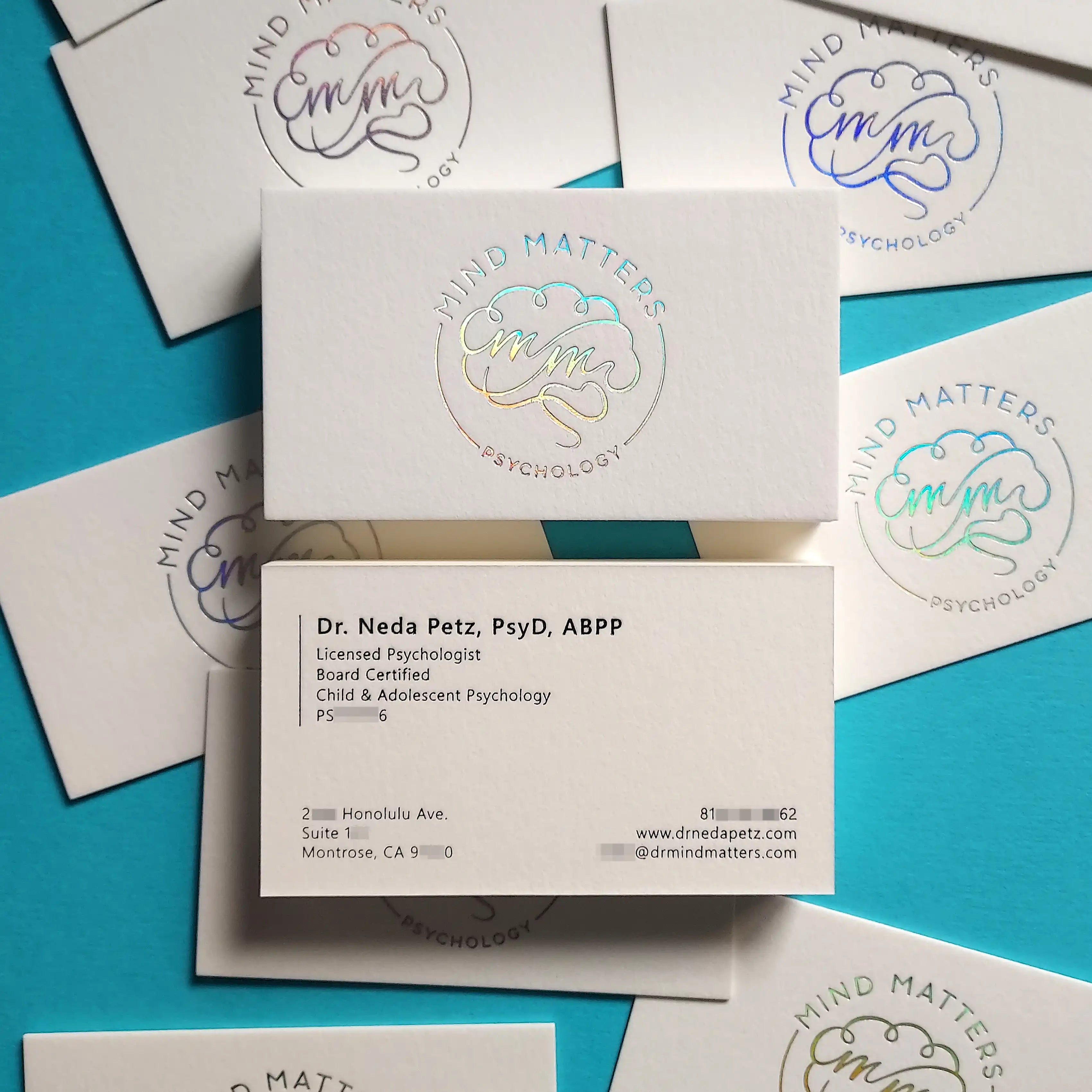 Business card with hologram foil logo and black foil text, placed under light to show reflective brilliance.