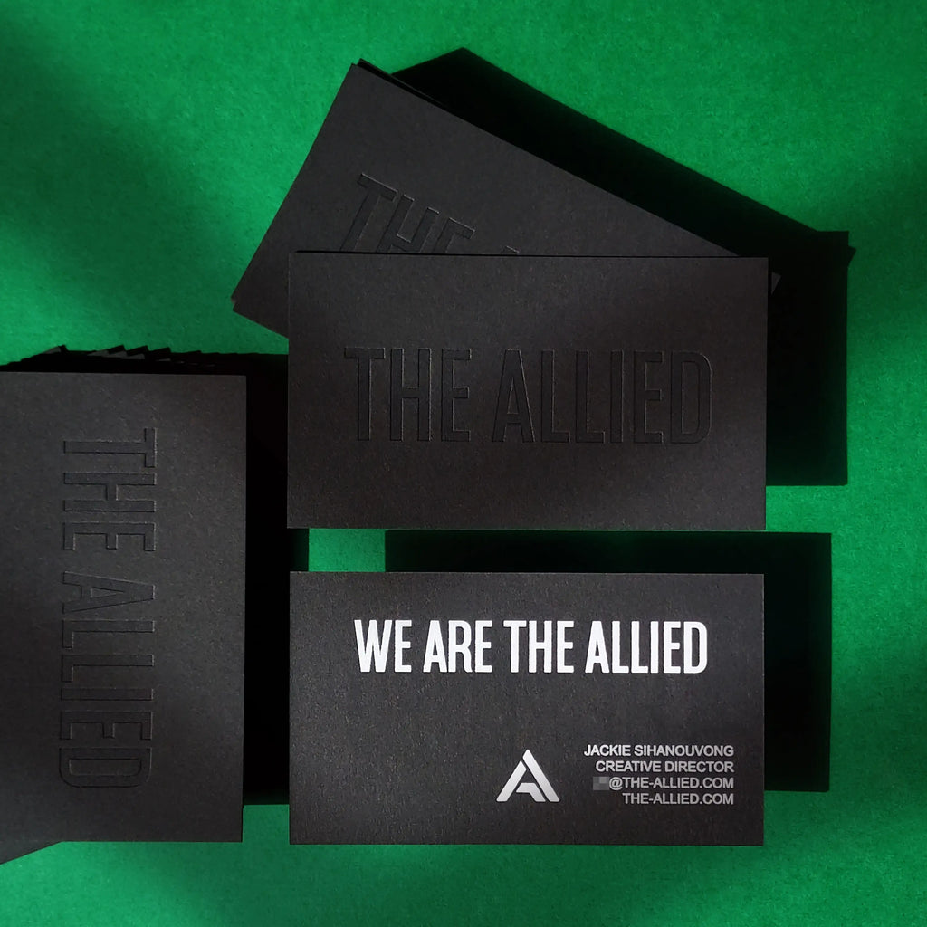 Black business cards with deep deboss texture and bright white foil on heavy 38pt 700gsm stock made by OddPlanPrint.