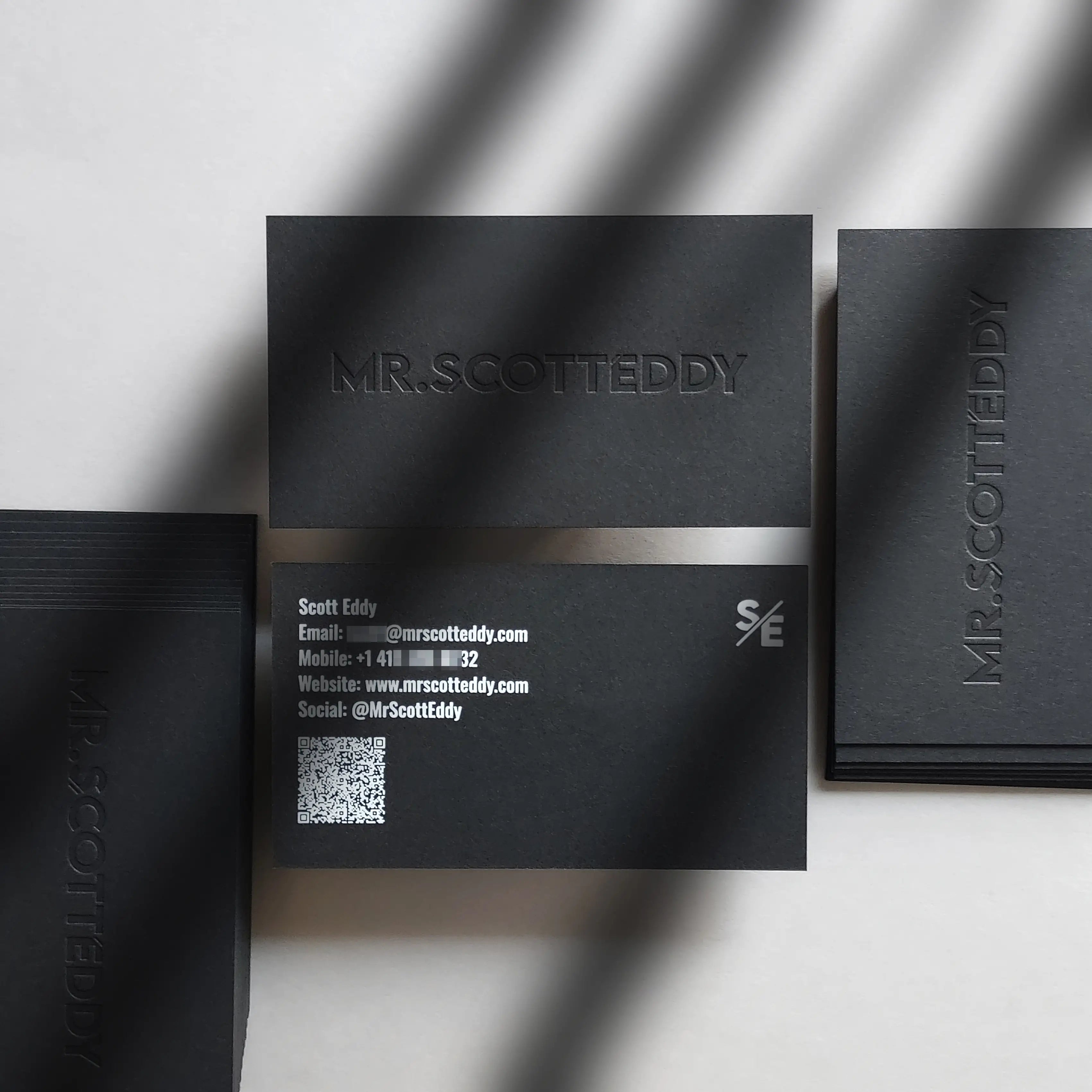 Custom black debossed business cards 38pt 700gsm with deboss, white printing and vCard QR code by OddPlanPrint.