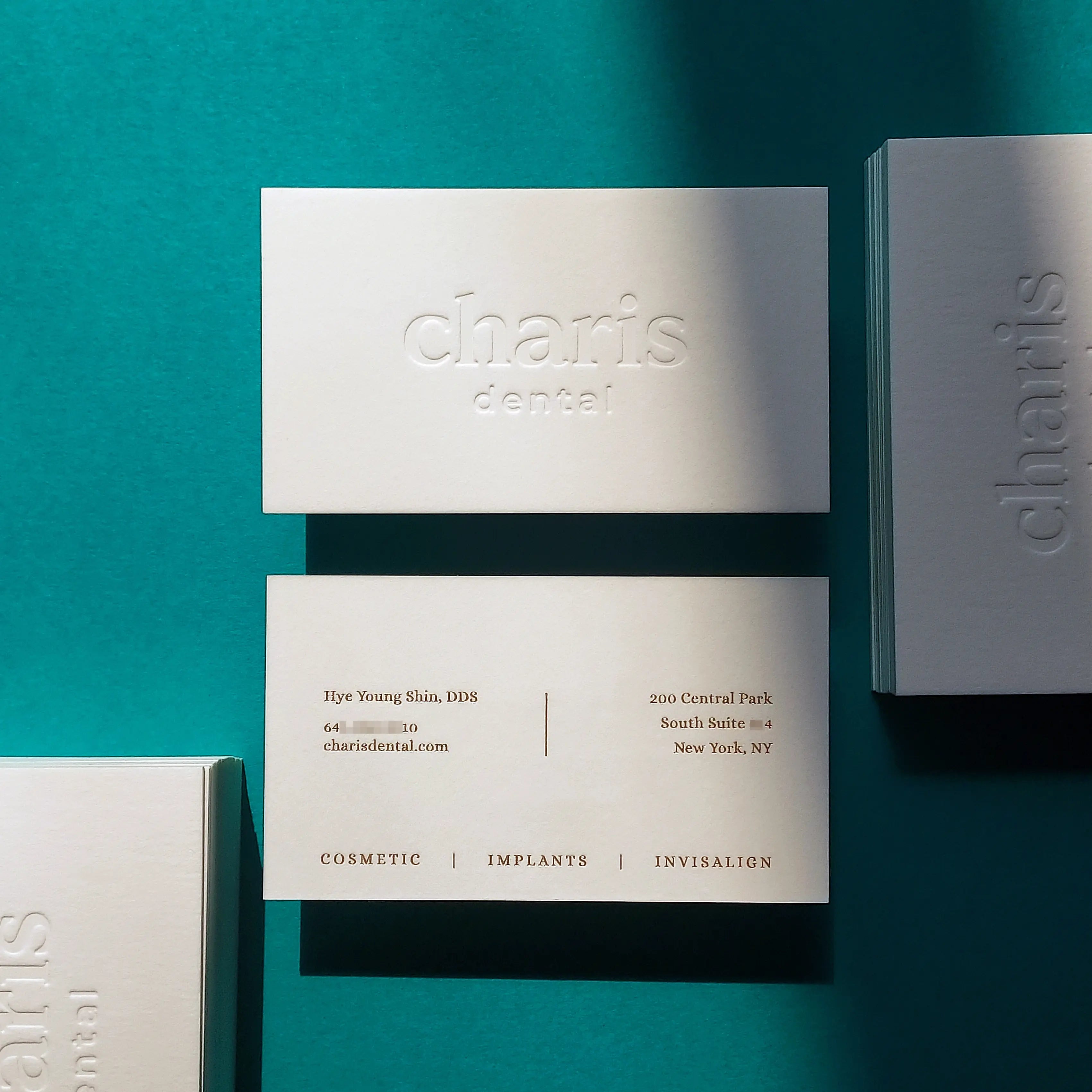 OddPlanPrint's 45pt cotton business card with a deep deboss and matte gold foil, highlighting its luxurious texture and subtle elegance.