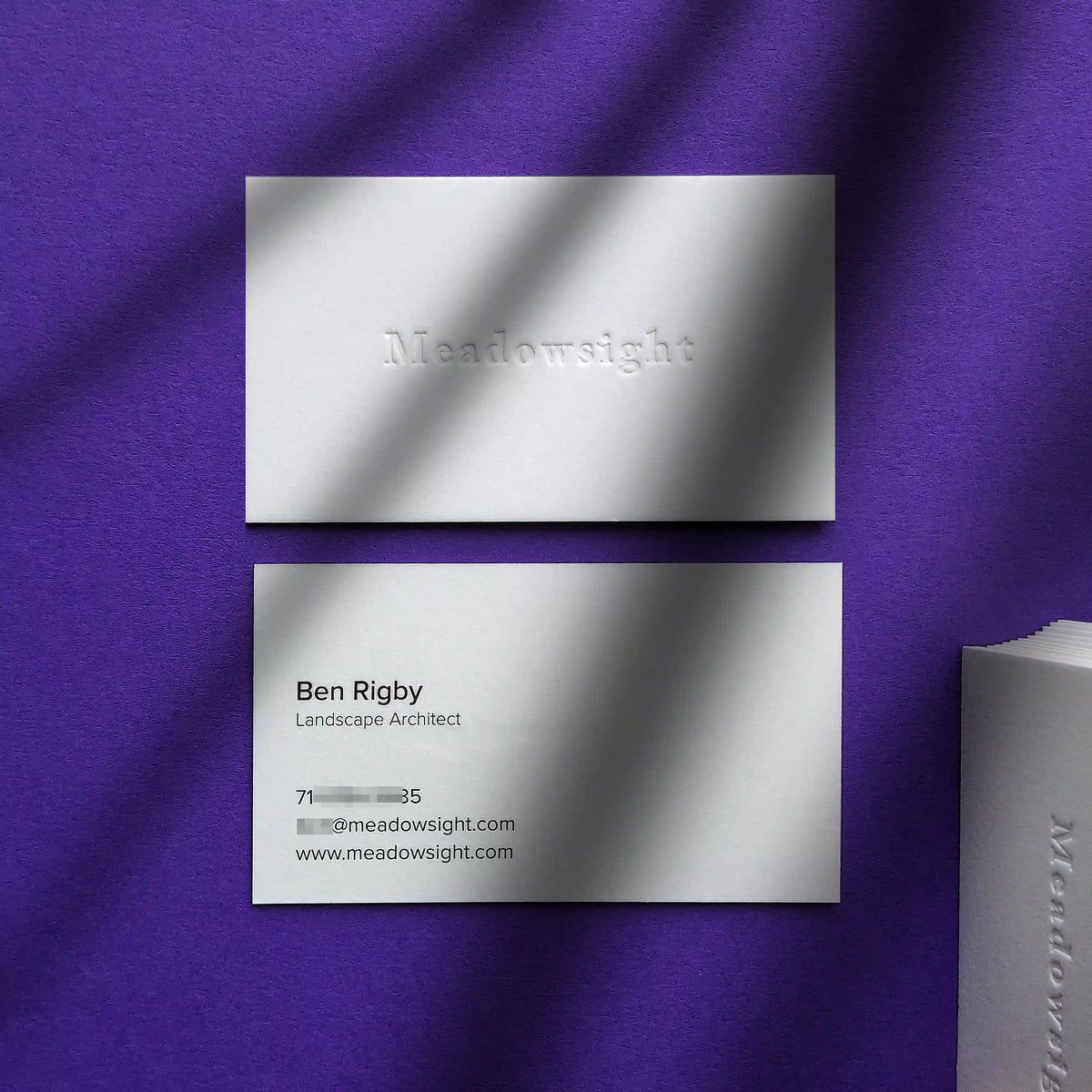 High-end 45pt cotton paper business cards with blind debossed texture and clean black text finished by OddPlanPrint.