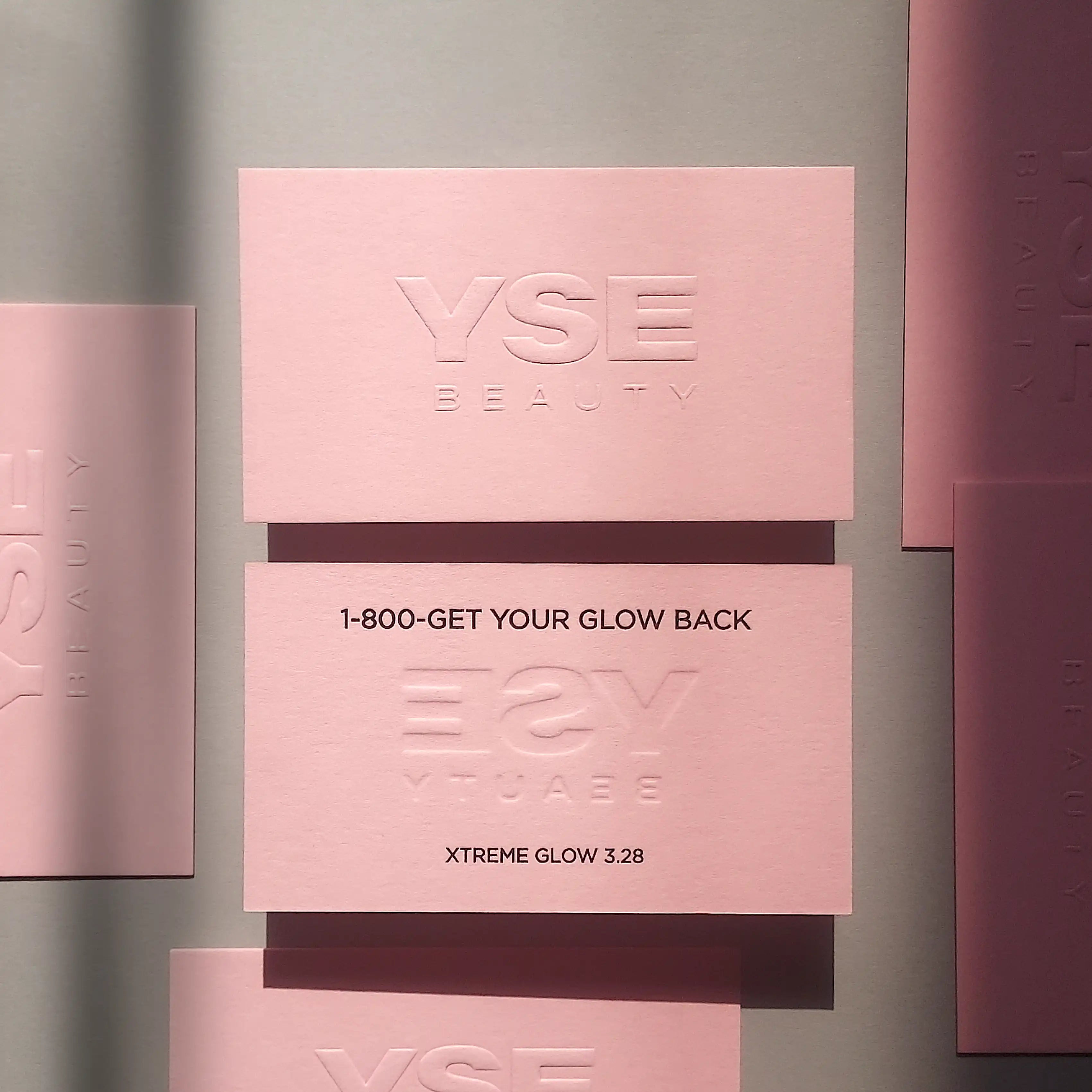 Soft pink business card featuring raised emboss printing and glossy black foil typography on thick 30pt stock, produced by OddPlanPrint.