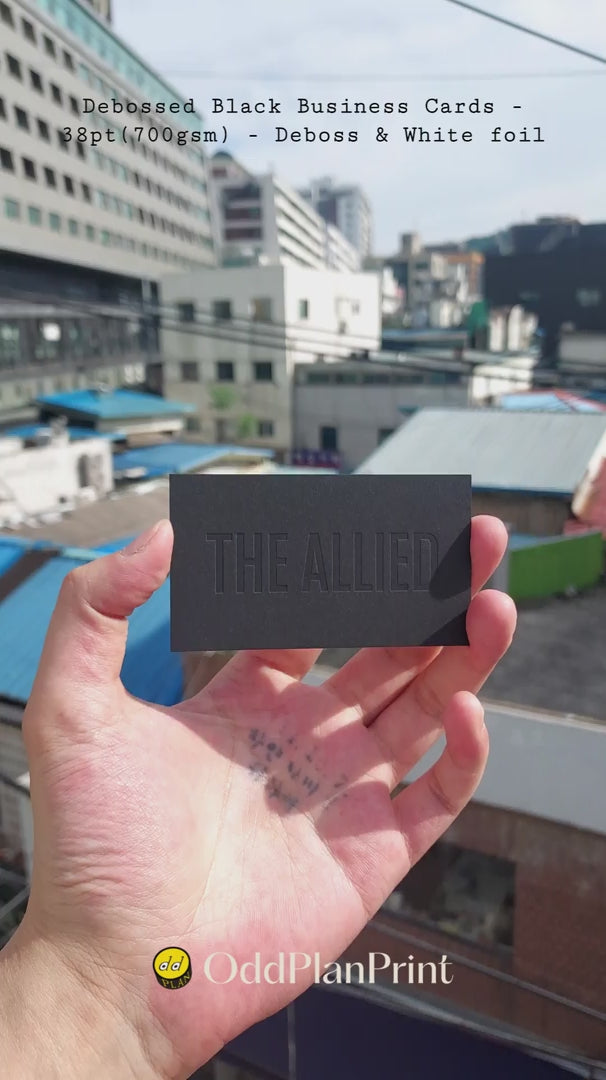 Refined 38pt black business cards combining tactile deboss with crisp white foil produced by OddPlanPrint.