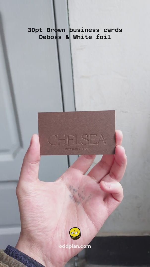 Two brown business cards overlapping, showing the clean edges of the 30pt stock and the crispness of the white foil stamping and deboss. from OddPlanPrint.