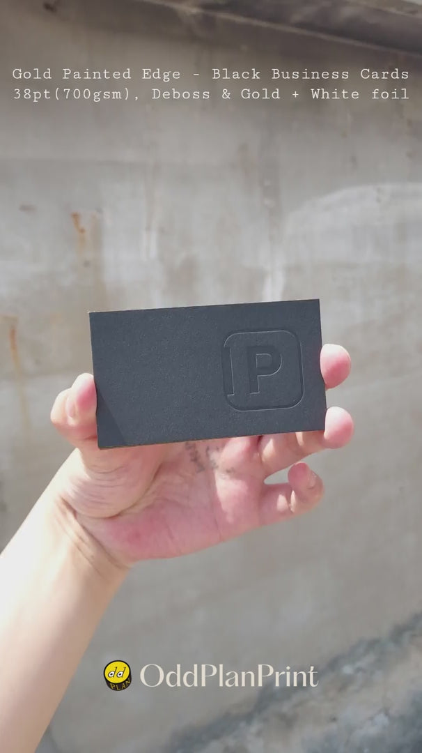 Premium 38pt black business cards by OddPlanPrint showcasing reflective gold painted edges paired with multi-foil stamping and deep blind deboss on 700gsm stock.