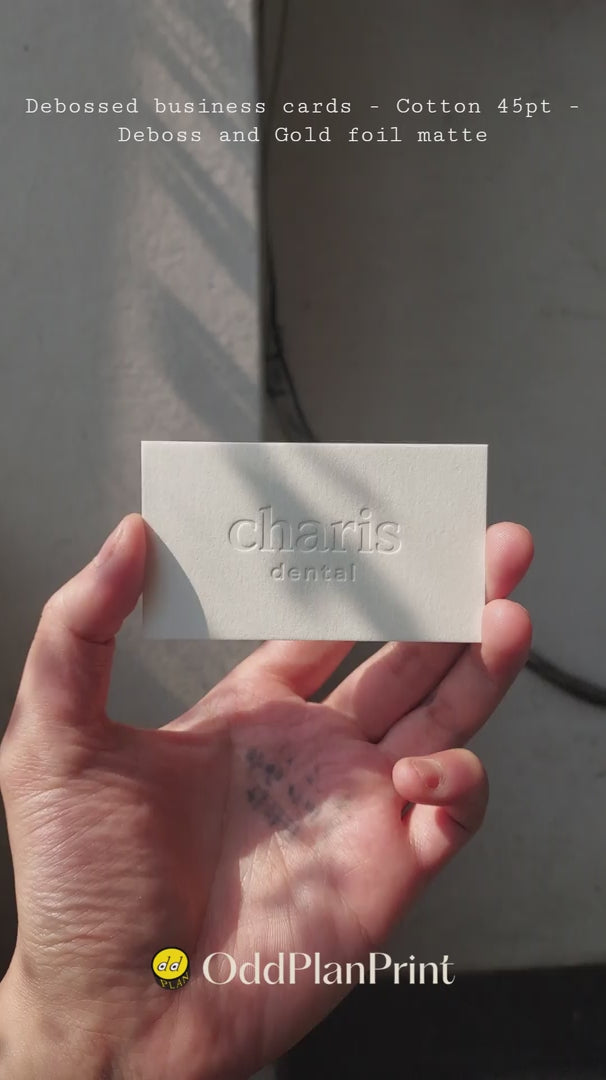 A luxurious 45pt cotton business card by OddPlanPrint, showcasing a deep deboss and a refined matte gold foil, conveying quiet power.
