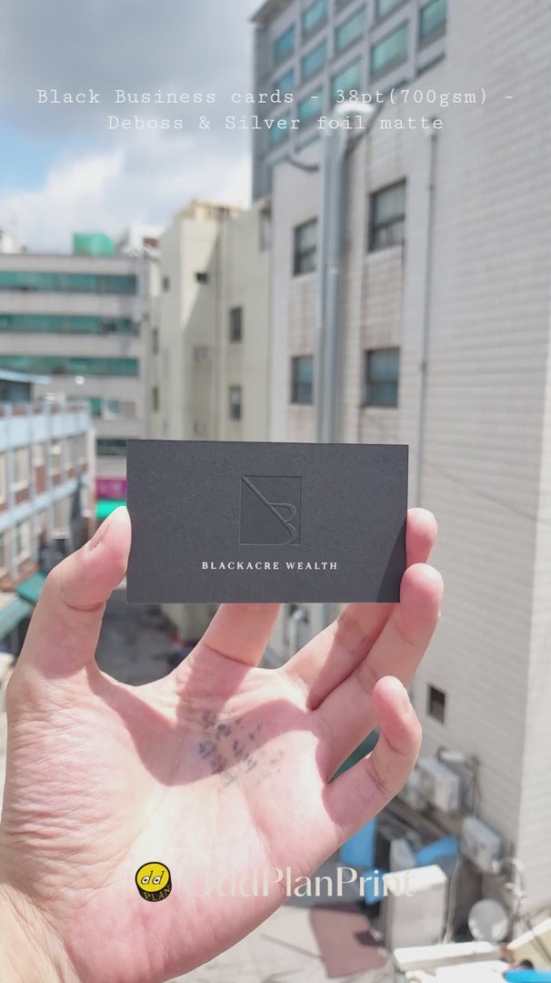 High-end 700gsm black cotton business cards from OddPlanPrint showcasing custom deep debossed text and metallic matte silver foil finish.