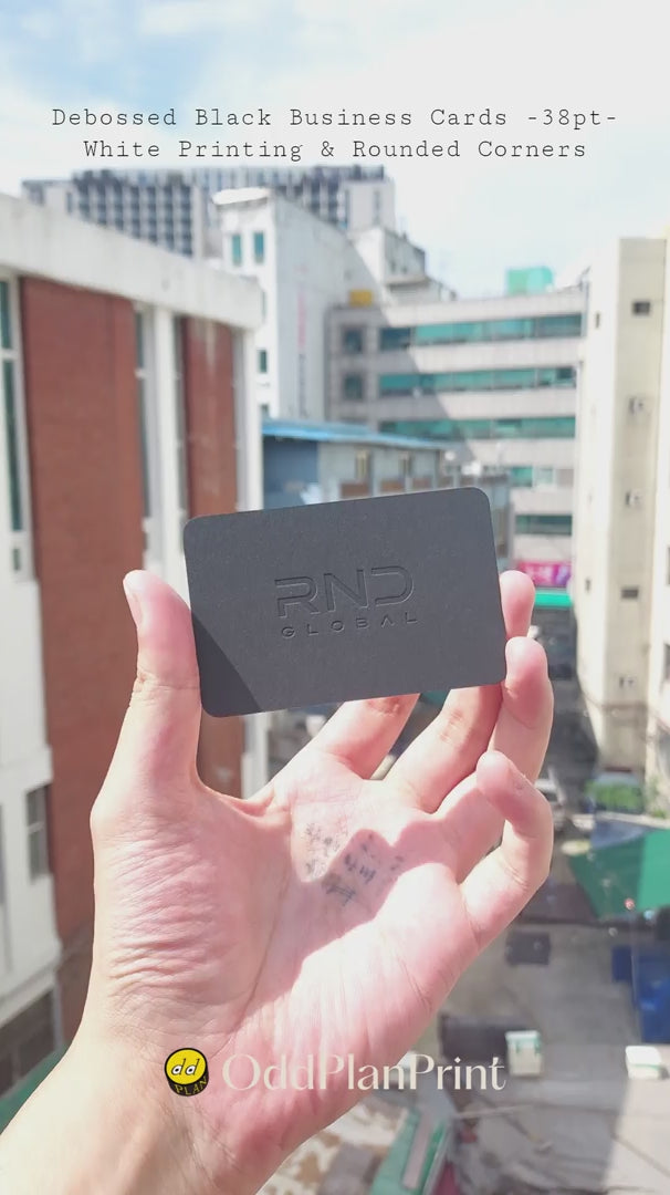 Luxury debossed black business cards showing white printing and rounded corners made by OddPlanPrint.