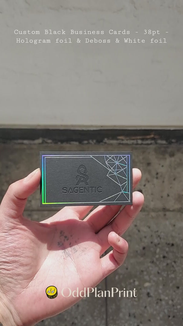 OddPlanPrint's custom 38pt black business card, uniquely illuminated by hologram foil, with a debossed texture and clear white foil details.