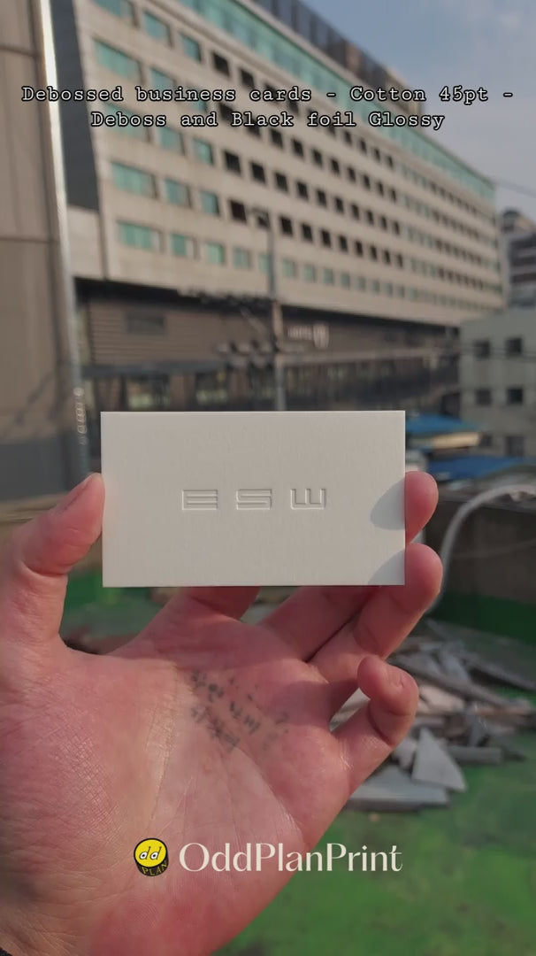 An elegant 45pt cotton business card by OddPlanPrint, featuring a debossed logo and a subtle black foil finish.